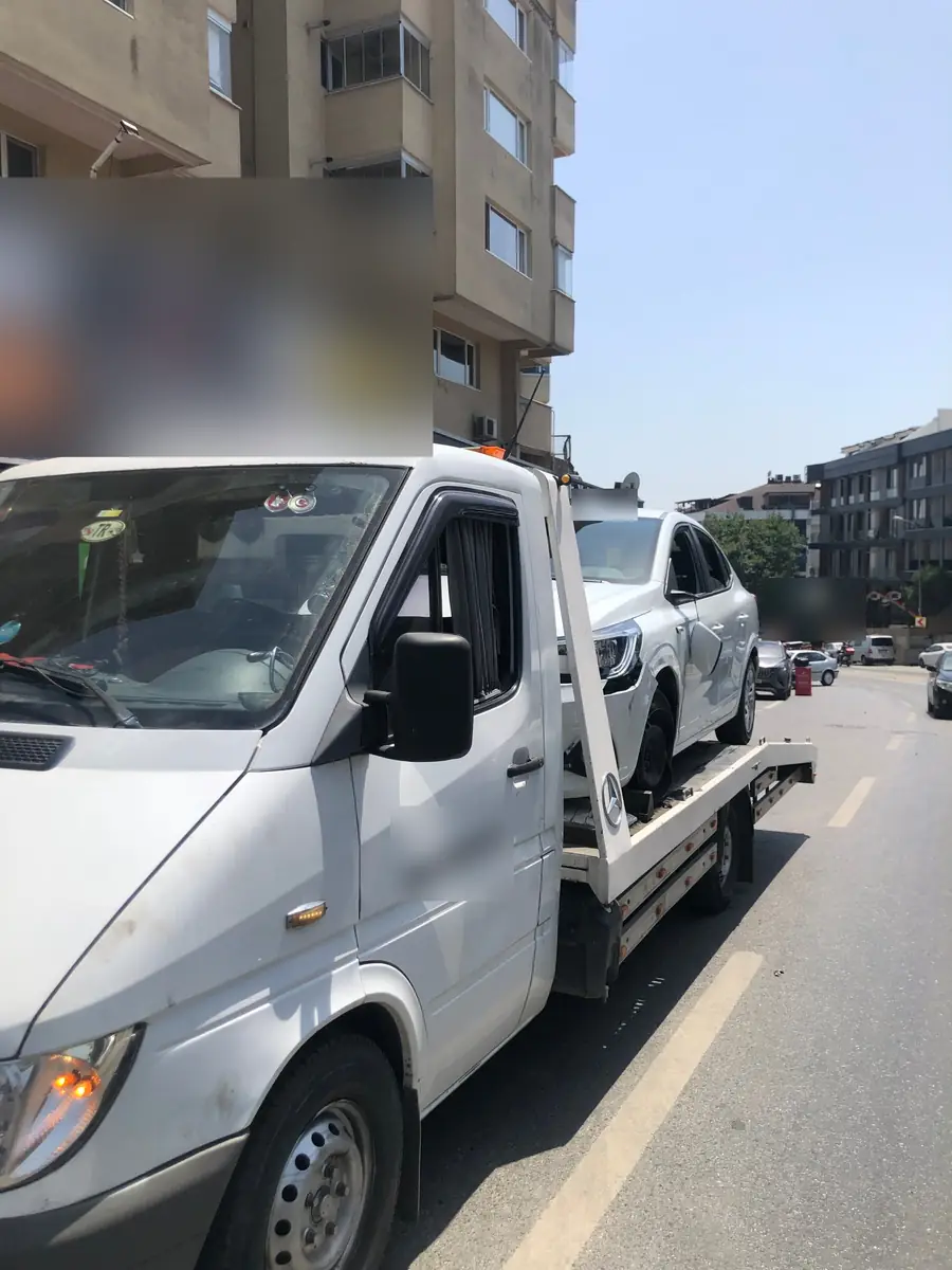 Gündüz cadde üzerinde çekiciye yüklenmiş ön tarafı hasarlı beyaz otomobil