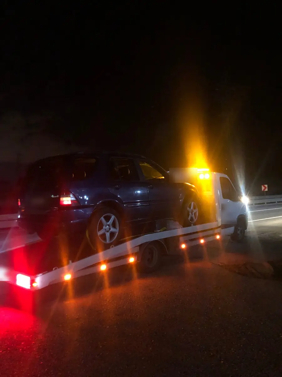 Gece yol kenarında çekici üzerinde SUV